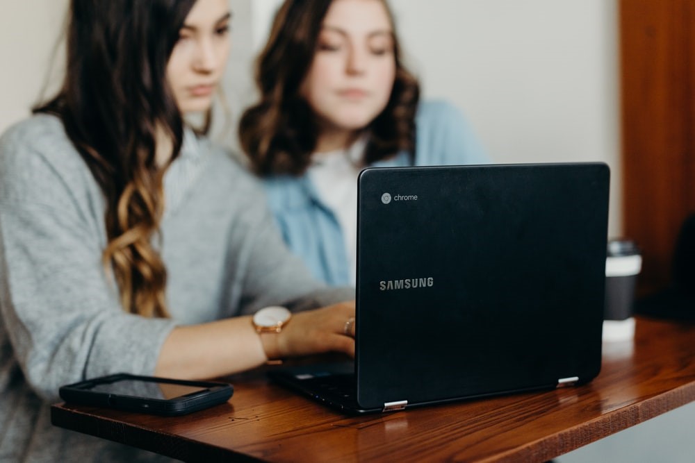 Estudantes sentados a mesa pesquisando formas de empreender durante a faculdade