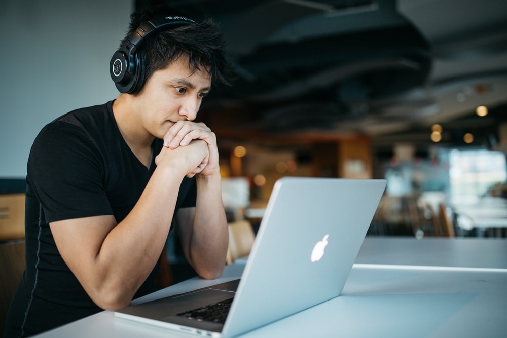 Homem sentado a mesa em frente ao notebook, pesquisando marketing digital o que é