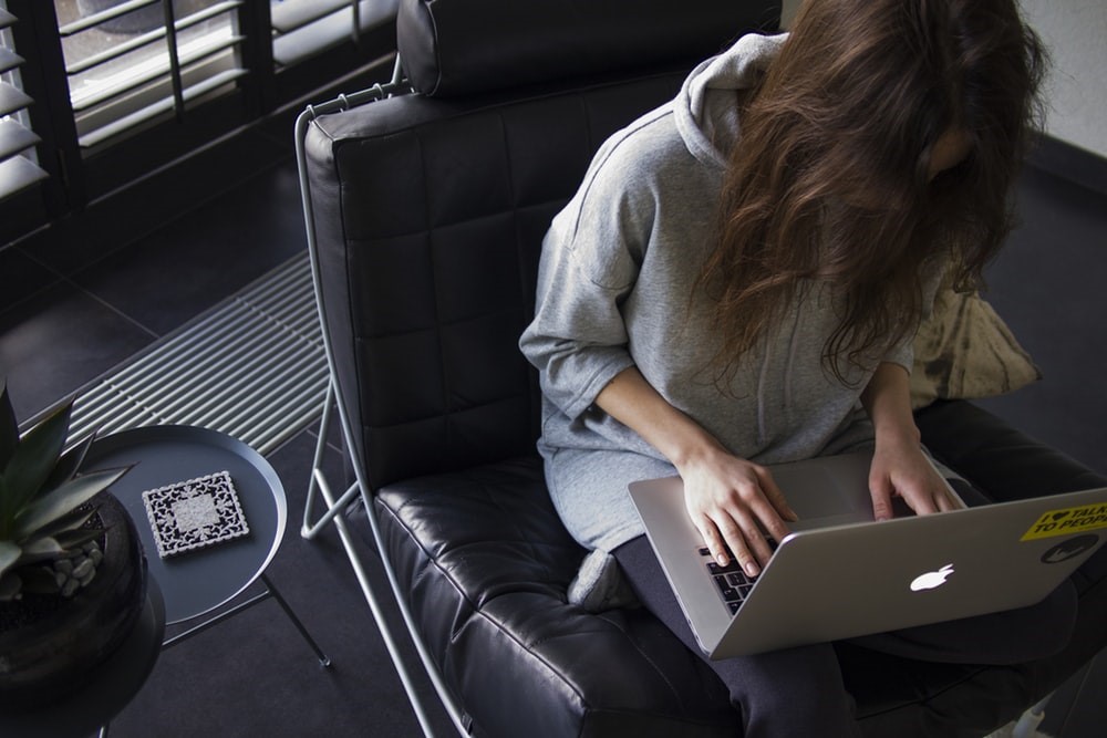 Pessoa sentada no sofa com notebook no colo trabalhando em casa