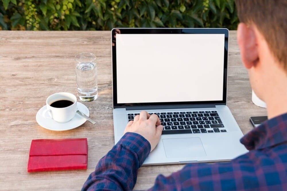Pessoa usando notebook para trabalho home office, em lugar com acesso a luz solar