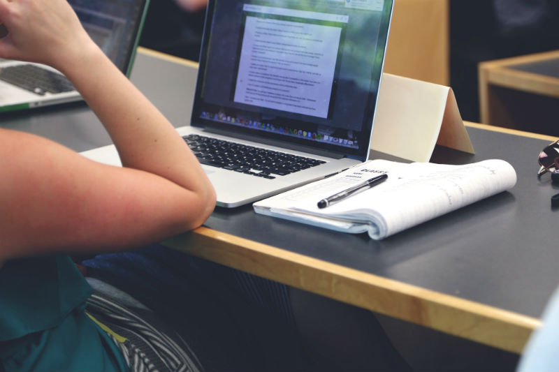 Pessoa sentada em frente ao notebook para fazer renda extra online durante a faculdade