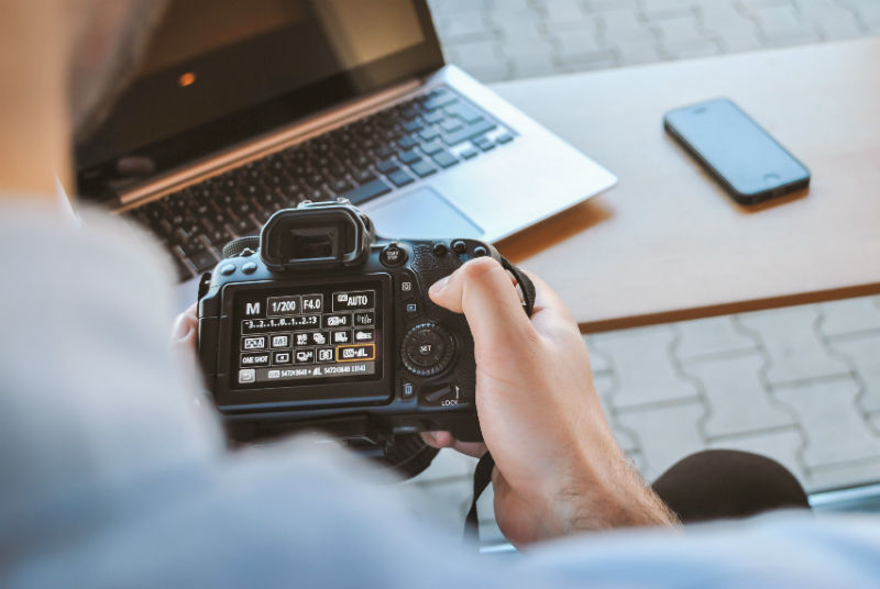 Estudante usando camera profissional para trabalhar em casa com venda de fotos