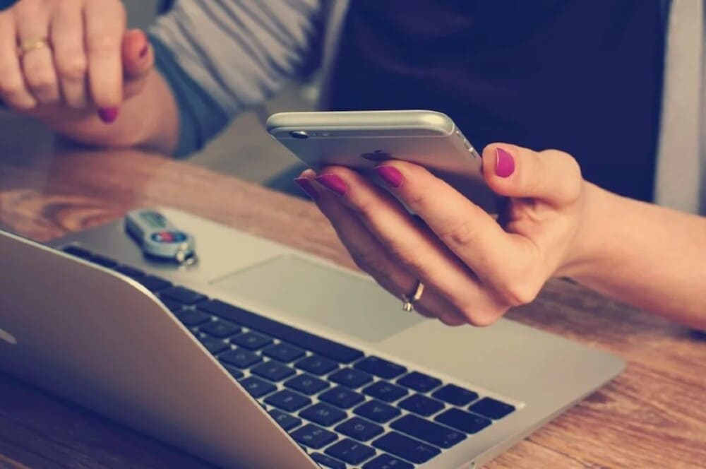 Pessoa usando computador e celular para trabalho em casa