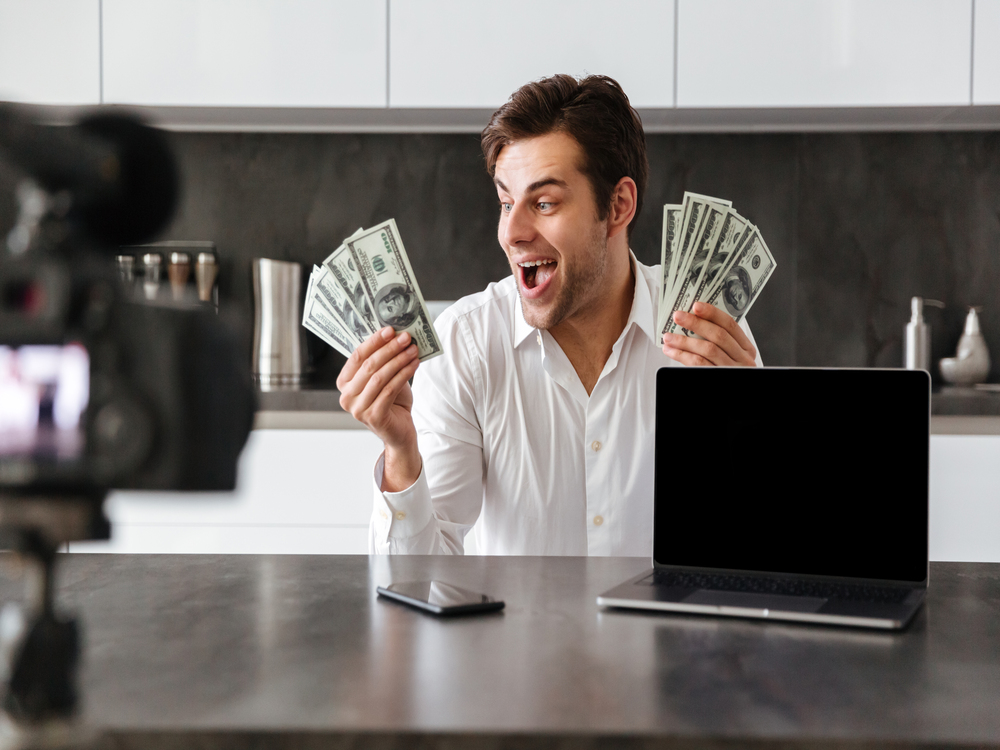 Homem feliz com dinheiro nas mãos demonstrando Como Ganhar Dinheiro com Marketing Digital Afiliado Eduzz